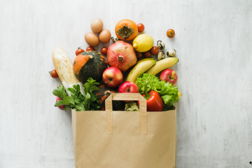 brown paper grocery bag with fruits and vegetables coming out of the top